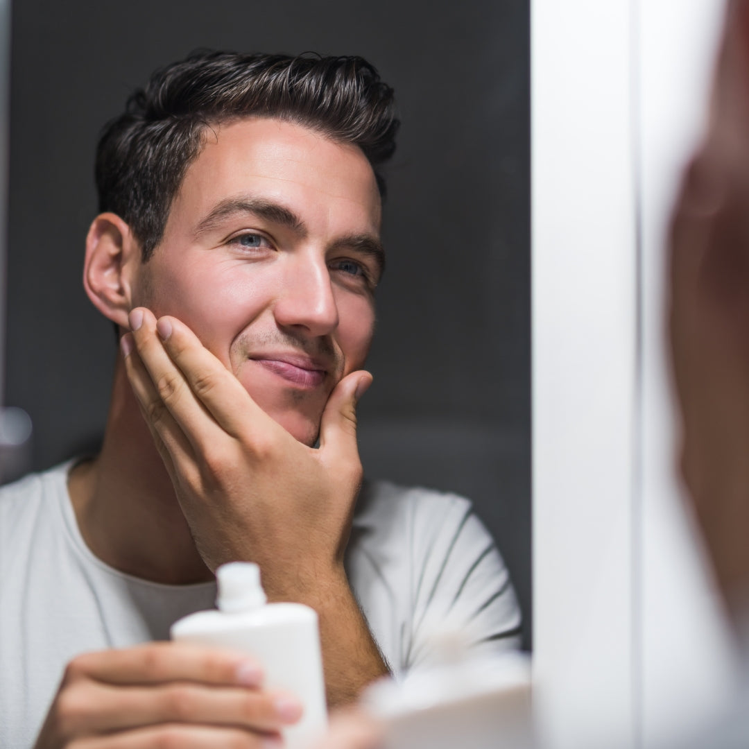 Man applying cream to his face in front of a mirror